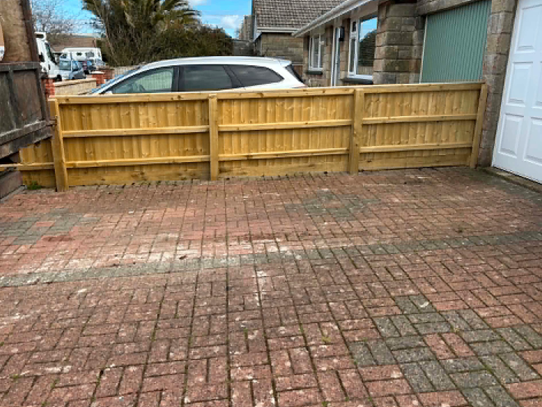 Newly installed fence panels on a cleared driveway